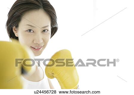 A young woman smiles with the gloves on as she poses against the camera View Large Photo Image Stock Photo - A young woman smiles with the gloves on as she poses against the camera. Fotosearch