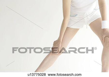 A young woman stretches her legs while exercising View Large Photo Image Stock Photo - A young woman stretches her legs while exercising. Fotosearch