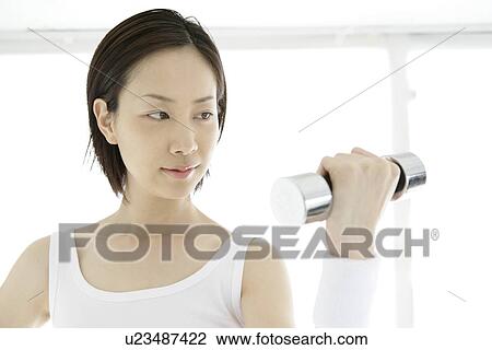Front view of a young woman lifting the dumbbell View Large Photo Image Stock Image - Front view of a young woman lifting the dumbbell. Fotosearch
