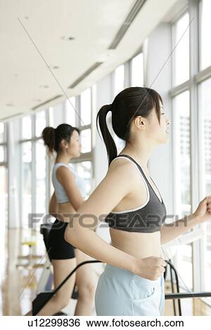Two young women exercise on a walker in a well equipped gym View Large Photo Image Stock Photograph - Two young women exercise on a walker in a well equipped gym. Fotosearch