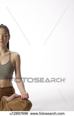 Stock Photograph - Front view of a young woman meditating in lotus position. Fotosearch