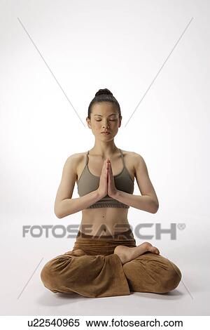 Stock Photography - Front view of a young woman meditating in lotus position. Fotosearch