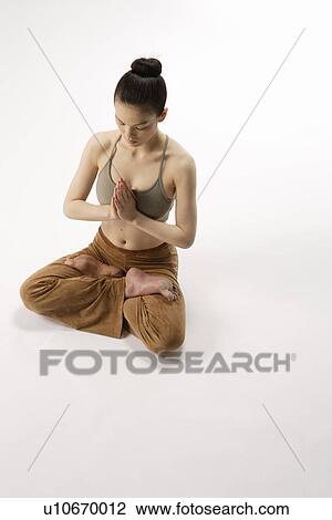 Stock Image - High angle view of a young woman in lotus position. Fotosearch