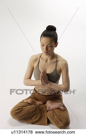 Stock Photo - High angle view of a young woman in lotus position. Fotosearch