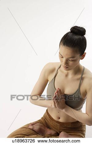 Stock Photograph - High angle view of a young woman in lotus position. Fotosearch