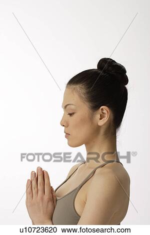 Stock Image - Side view of a young woman meditating. Fotosearch