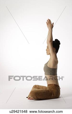 Stock Photo - Side view of a young woman meditating in lotus position. Fotosearch