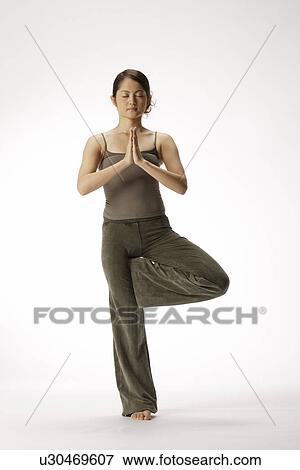 Stock Photo - View of a young woman in tree position. Fotosearch