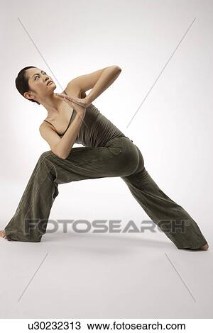 Stock Image - View of a young woman stretching her body. Fotosearch