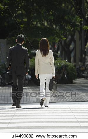 Stock Image - Rear view of professionals walking during the day. Fotosearch