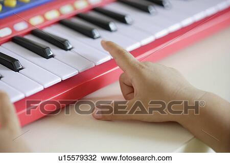 Stock Image - A child playing a toy organ. Fotosearch
