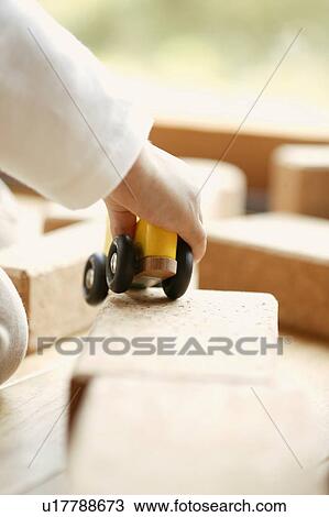 Stock Image - A child running his toy car on rectangular slabs. Fotosearch