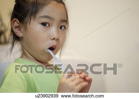 Stock Photo - A girl brushing teeth. Fotosearch