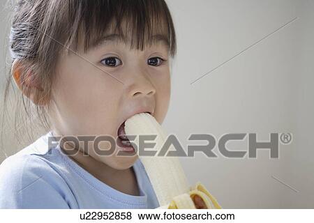 Stock Photo - A girl eating banana. Fotosearch