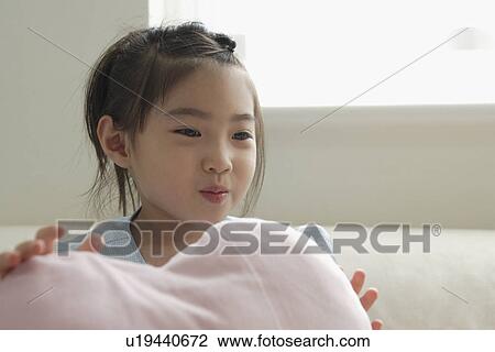A girl holding a cushion on sofa View Large Photo Image Stock Image - A girl holding a cushion on sofa. Fotosearch