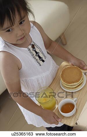 Stock Image - A girl holding a tray with some pancakes. Fotosearch