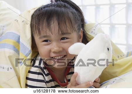 Stock Photo - A girl in bed with a soft doll. Fotosearch