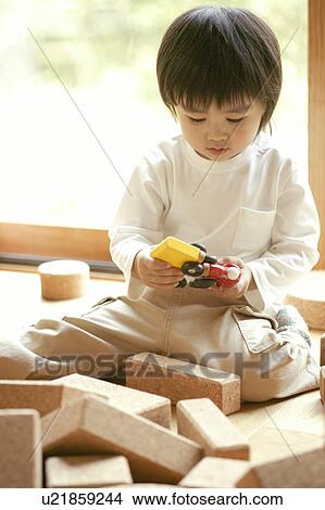 Picture - A small boy playing with a toy and some rectangular slabs. Fotosearch