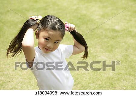 Stock Photo - A young girl showing her ponytails in front of the camera. Fotosearch