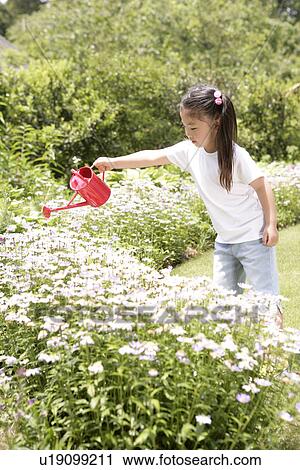 Stock Image - A young girl watering the flowers in the garden. Fotosearch