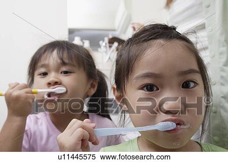 Stock Photography - Sisters brushing teeth. Fotosearch