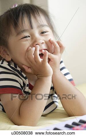 Stock Photo - Smiling girl with a toy organ. Fotosearch