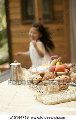 Some foodstuff kept on a table as a girl moves from the side View Large Photo Image Stock Photo - Some foodstuff kept on a table as a girl moves from the side. Fotosearch