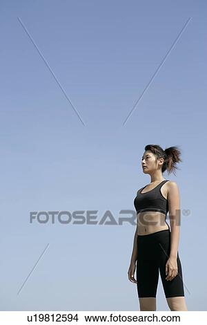 Picture - A side view of a woman in workout suit seen under the sky. Fotosearch
