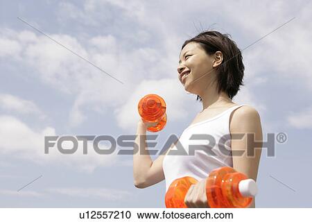 A woman exercising as she lifts the dumbbells View Large Photo Image Stock Image - A woman exercising as she lifts the dumbbells. Fotosearch