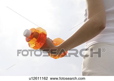 A woman lifts a dumbbell while exercising View Large Photo Image Stock Image - A woman lifts a dumbbell while exercising. Fotosearch
