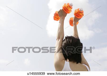A woman raises the dumbbells straight up View Large Photo Image Stock Photo - A woman raises the dumbbells straight up. Fotosearch