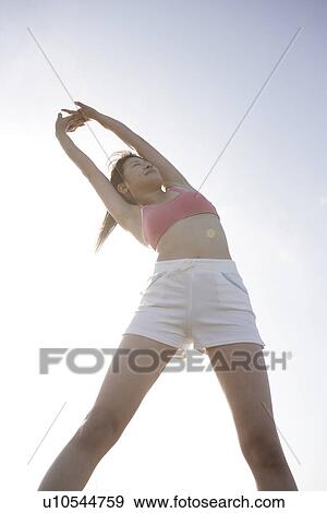 Stock Photo - A woman stretching herself during bright sunlight. Fotosearch