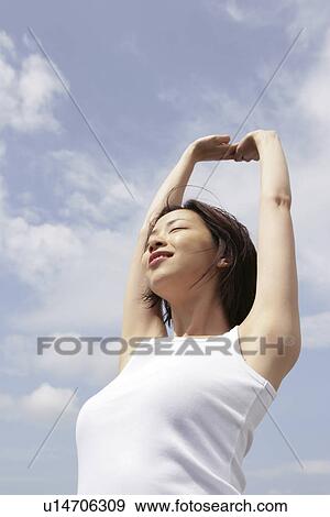 Stock Photo - A woman stretching herself under the sky. Fotosearch