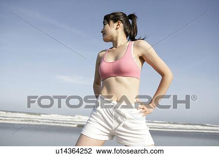 Stock Image - A young woman exercising on the seashore. Fotosearch