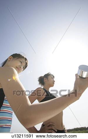 Stock Image - A young woman holds the dumbbell as her mate looks on. Fotosearch