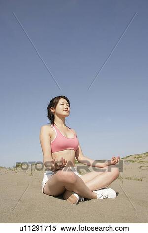 Stock Photography - A young woman meditating in the desert. Fotosearch