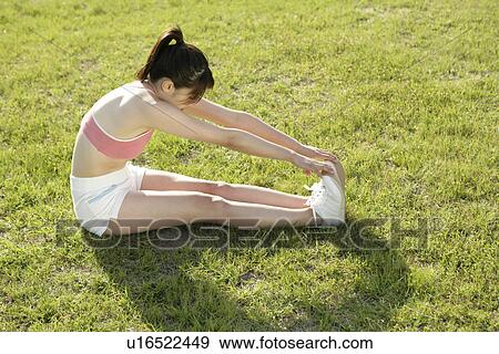 A young woman stretching her hands till her toes while exercising View Large Photo Image Stock Photo - A young woman stretching her hands till her toes while exercising. Fotosearch