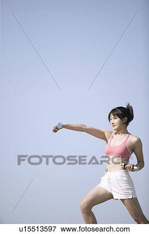 A young woman works out with the help of the dumbbells View Large Photo Image Stock Photo - A young woman works out with the help of the dumbbells. Fotosearch