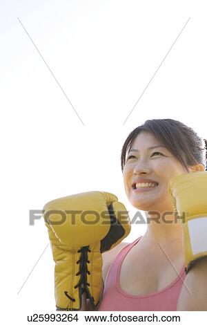Picture - An ecstatic woman wearing her boxing gloves seen under the sky. Fotosearch