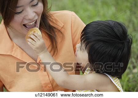 A boy feeding his mother View Large Photo Image Stock Image - A boy feeding his mother. Fotosearch