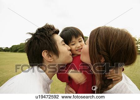 Stock Image - A couple kiss their son amidst a vast ground. Fotosearch