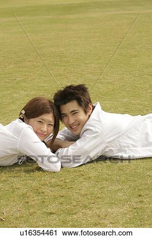 Stock Image - A couple lying in the garden faces the camera. Fotosearch