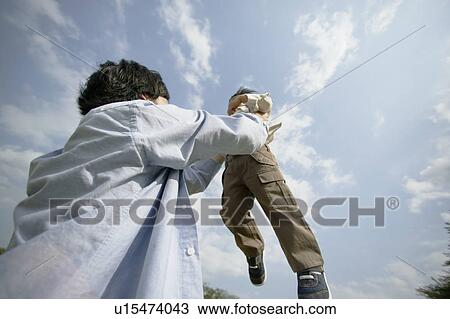 Stock Image - A father lifting his son in air. Fotosearch