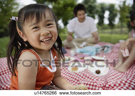 A girl having lunch by the trees with her family View Large Photo Image Stock Photograph - A girl having lunch by the trees with her family. Fotosearch