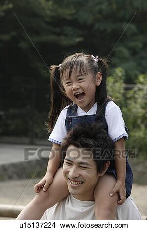 Picture - A girl riding her father's shoulders. Fotosearch