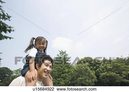 Stock Image - A girl riding her father's shoulders. Fotosearch