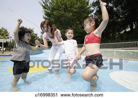 Stock Image - A mother playing with three children in pool. Fotosearch