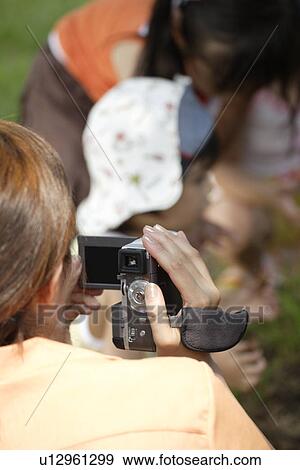 Stock Photo - A mother shooting video. Fotosearch