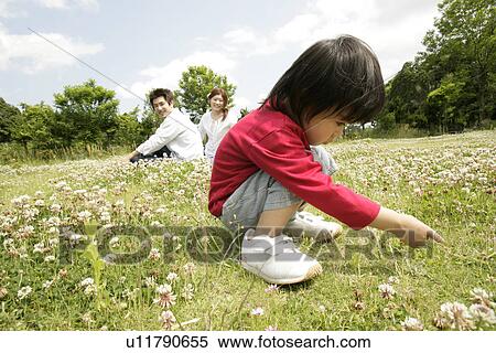 Stock Photography - A small boy stares at the grass in the garden as his parents looks on. Fotosearch