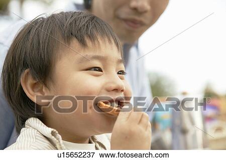 A small boy takes a bite of a foodstuff View Large Photo Image Stock Photo - A small boy takes a bite of a foodstuff. Fotosearch